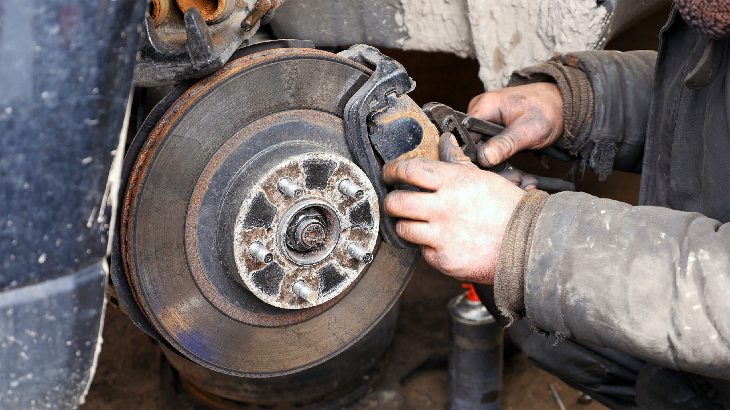 Auto mechanic working on brakes in car repair shop